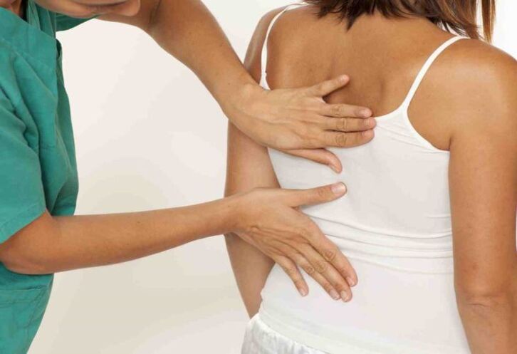 the doctor examines the back with pain in the shoulder blades